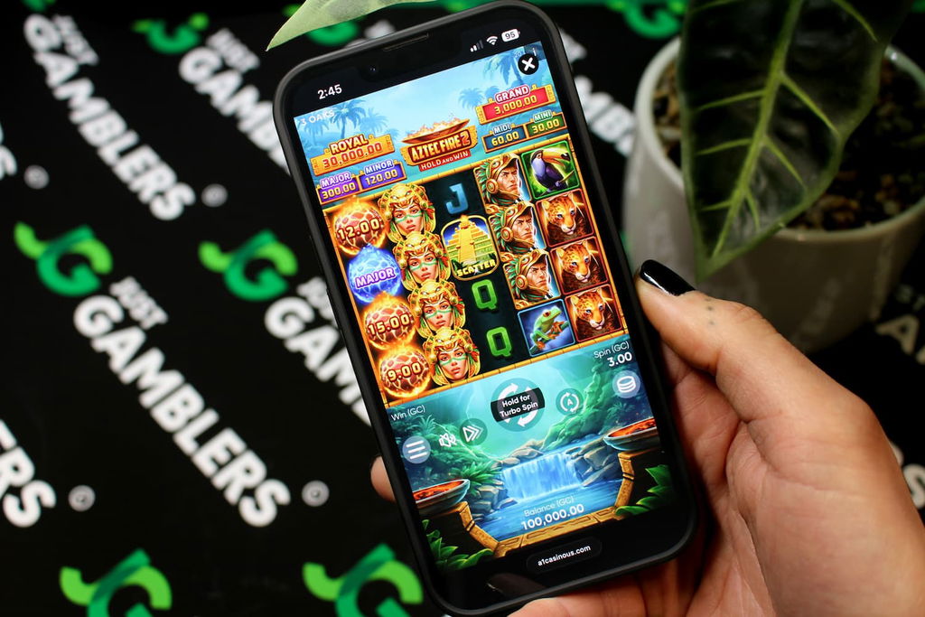 Angela Zillich holding an iPhone with the A1 casino mobile in-game page loaded on the webpage.