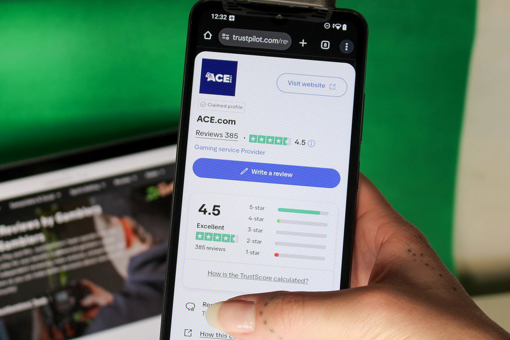 Angela Zillich holding an iPhone with the Ace casino Trustpilot page loaded on the webpage.