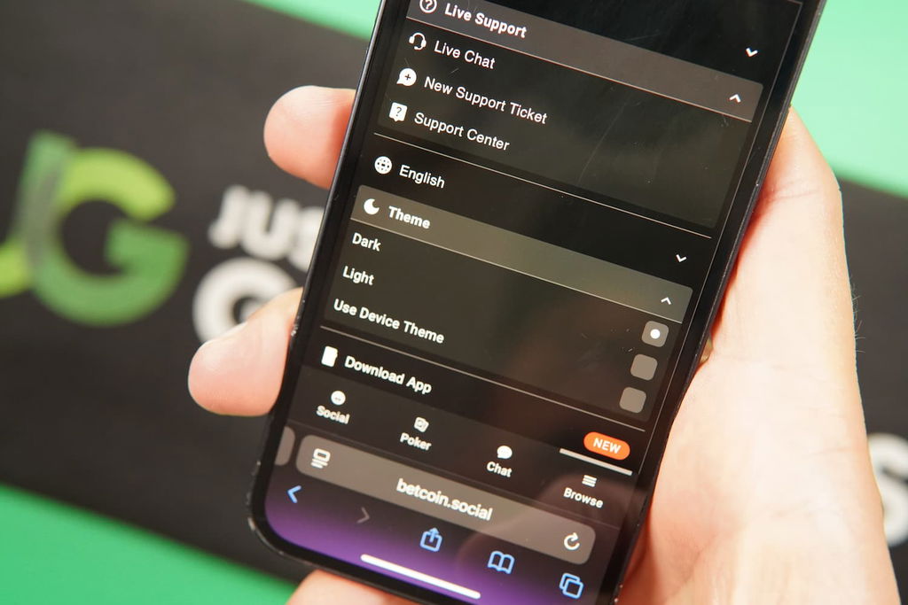 Patrik Lidin holding an iPhone with the BetcoinSocial casino dark light mode page loaded on the webpage.