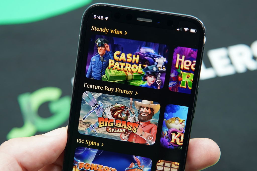 Patrik Lidin holding an iPhone with the BettySweeps casino game library page loaded on the webpage.