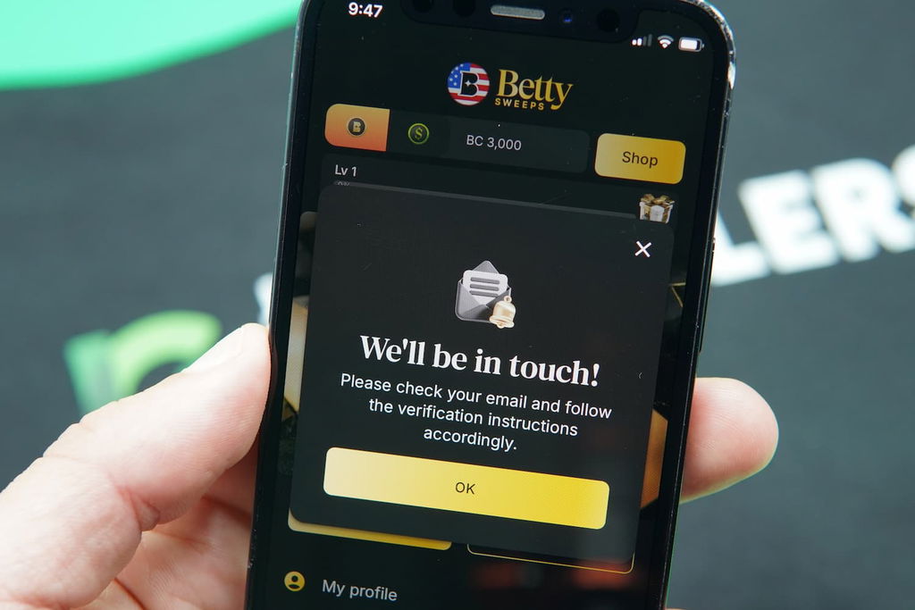 Patrik Lidin holding an iPhone with the BettySweeps casino KYC page loaded on the webpage.