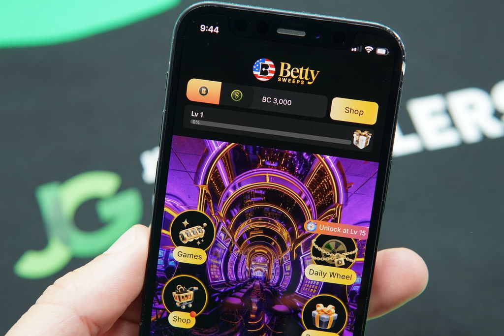 Patrik Lidin holding an iPhone with the BettySweeps casino landing page loaded on the webpage.
