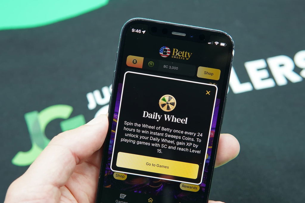 Patrik Lidin holding an iPhone with the BettySweeps casino promotions page loaded on the webpage.