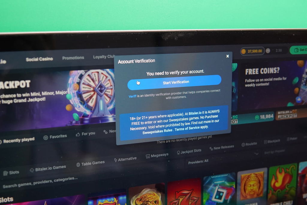 Patrik Lidin holding an iPhone with the Bitsler.io casino kyc page loaded on the webpage.
