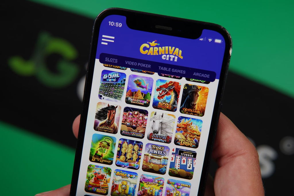 Patrik Lidin holding an iPhone with the Carnival Citi casino game library page loaded on the webpage.