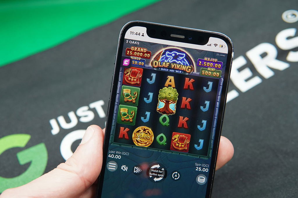 Patrik Lidin holding an iPhone with Cashoomo casino game Olaf Viking showing.