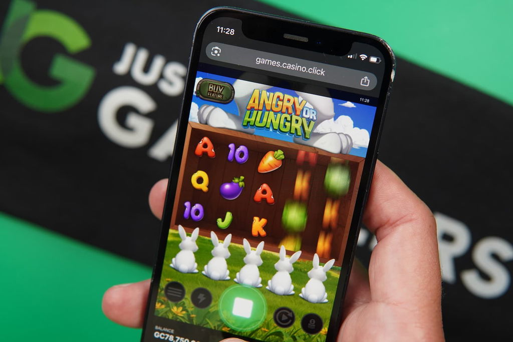 Patrik Lidin holding an iPhone with the Casino Click casino in-game mobile page loaded on the webpage.