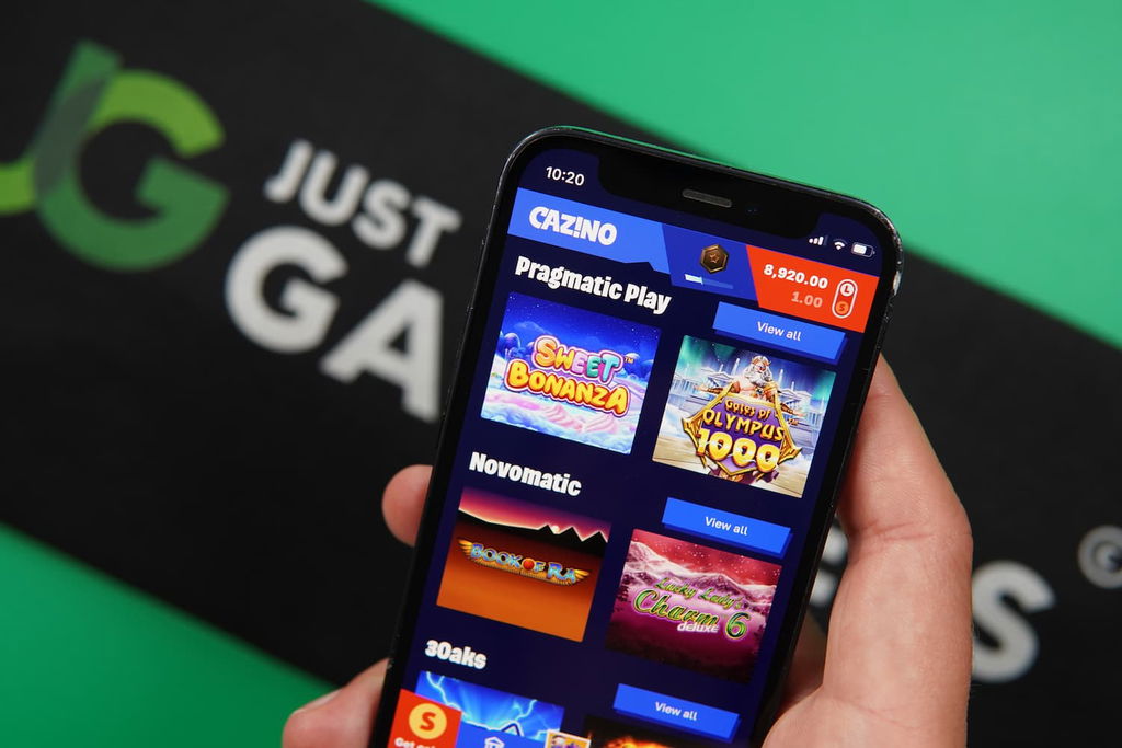 Patrik Lidin holding an iPhone with the Cazino casino game library page loaded on the webpage.