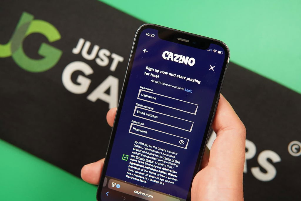 Patrik Lidin holding an iPhone with the Cazino casino registration page loaded on the webpage.