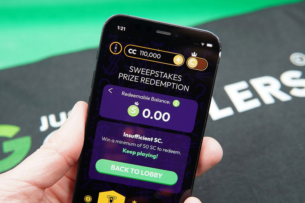 Patrik Lidin holding an iPhone with the Crown Coins Casino redemptions loaded on the webpage.