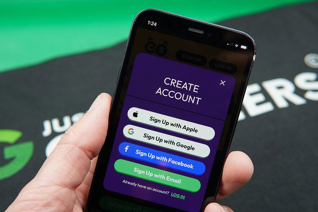 Patrik Lidin holding an iPhone showing the Crown Coins Casino registration process.