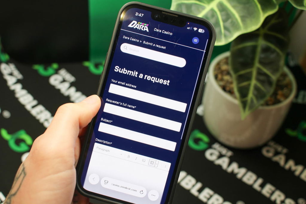 Angela Zillich holding an iPhone with the Dara casino Customer Support page loaded on the webpage.
