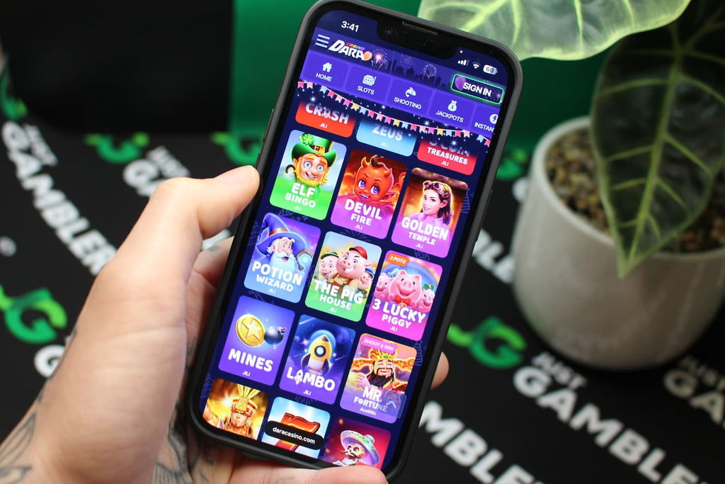 Angela Zillich holding an iPhone with the Dara casino gaming lobby page loaded on the webpage.