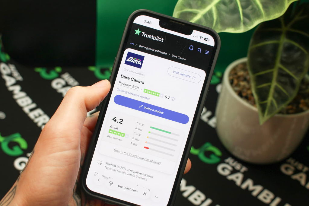 Angela Zillich holding an iPhone with the Dara casino Trustpilot page loaded on the webpage.