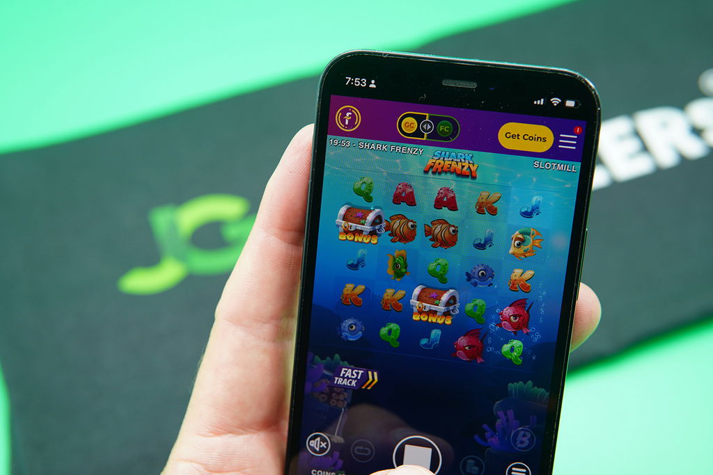 Patrik Lidin holding an iPhone with McLuck casino game Shark Frenzy showing.