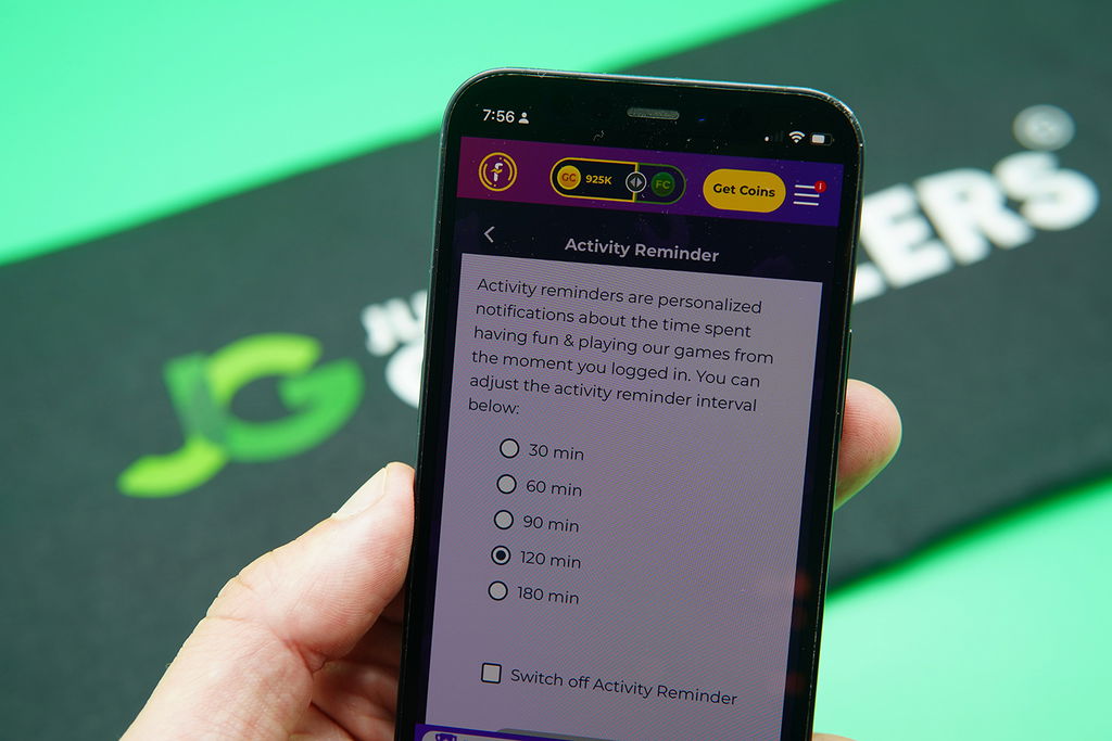 Patrik Lidin holding an iPhone with the Fortune Coins responsible gambling page showing.