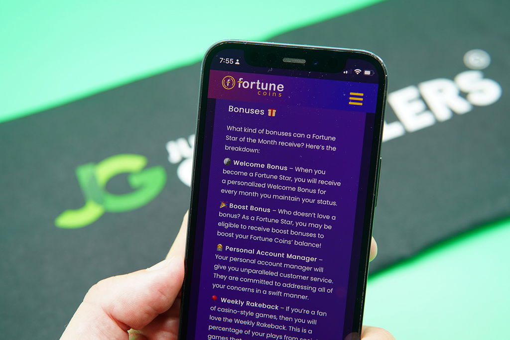 Patrik Lidin holding an iPhone showing the Fortune Coins VIP program on the webpage.