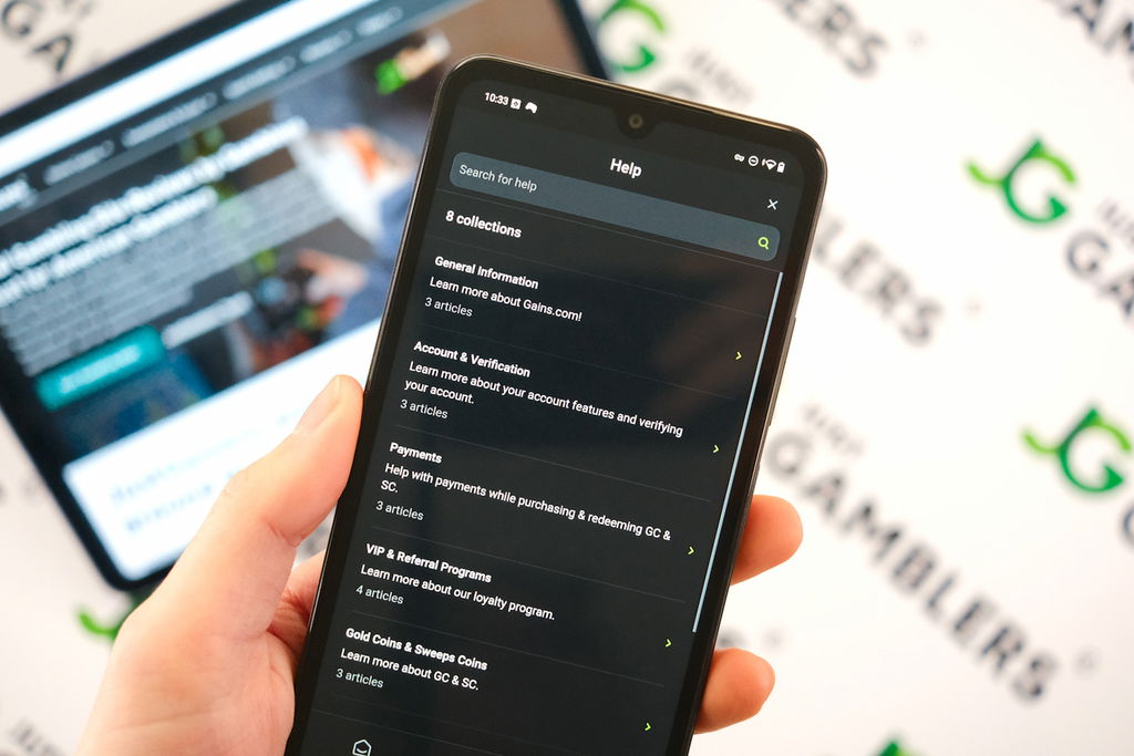Angela Zillich holding an Android Phone with the Gains casino FAQ Collections page loaded on the webpage.