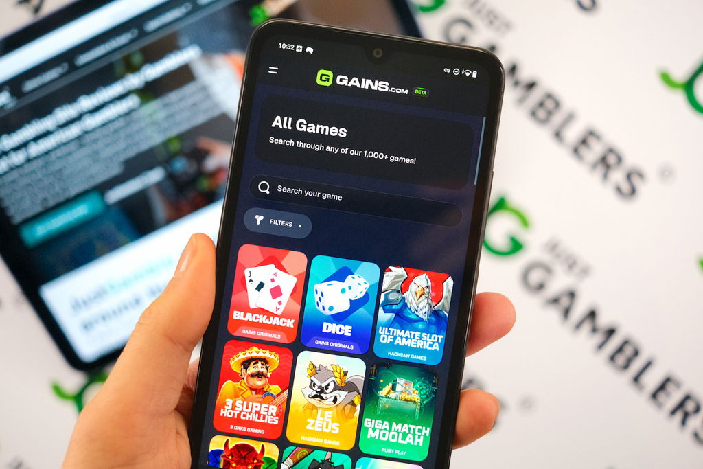 Angela Zillich holding an Android Phone with the Gains casino gaming library page loaded on the webpage.