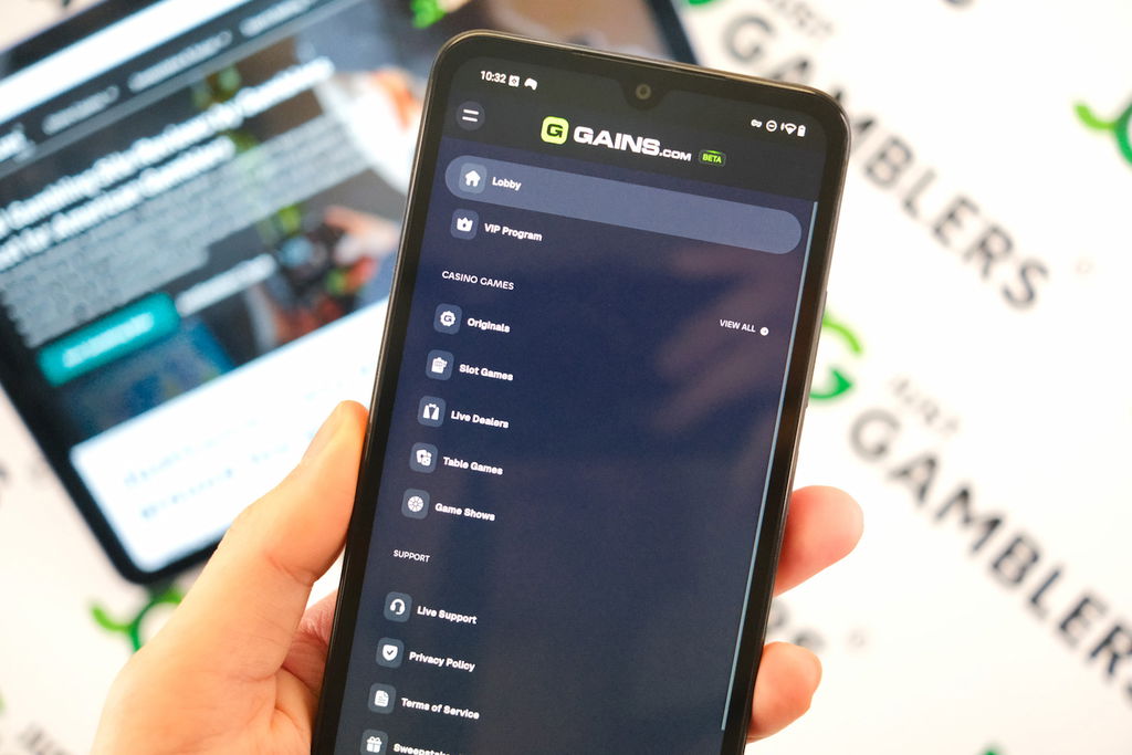 Angela Zillich holding an Android Phone with the Gains casino Menu page loaded on the webpage.