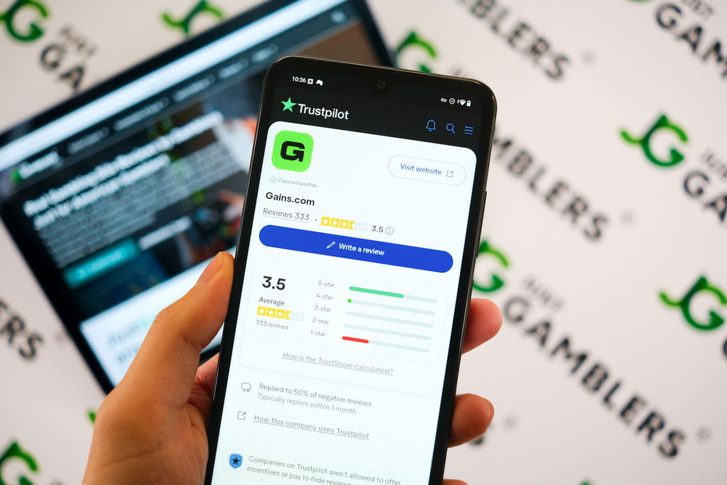 Angela Zillich holding an Android Phone with the Gains casino Trustpilot ratings page loaded on the webpage.