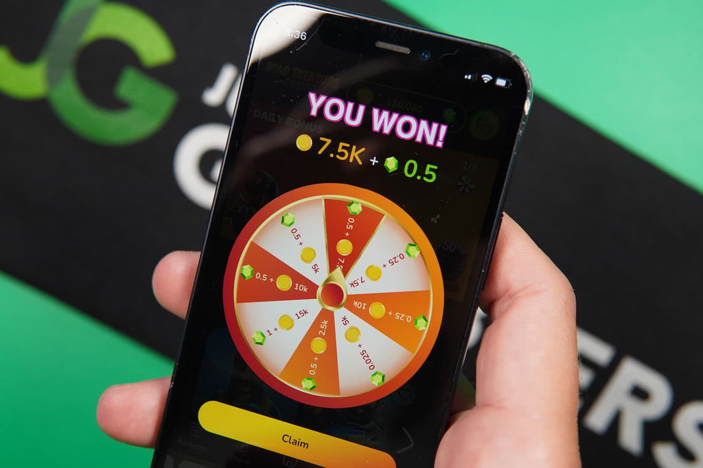 Patrik Lidin holding an iPhone with the Gold Treasure casino Daily Reward page loaded on the webpage.