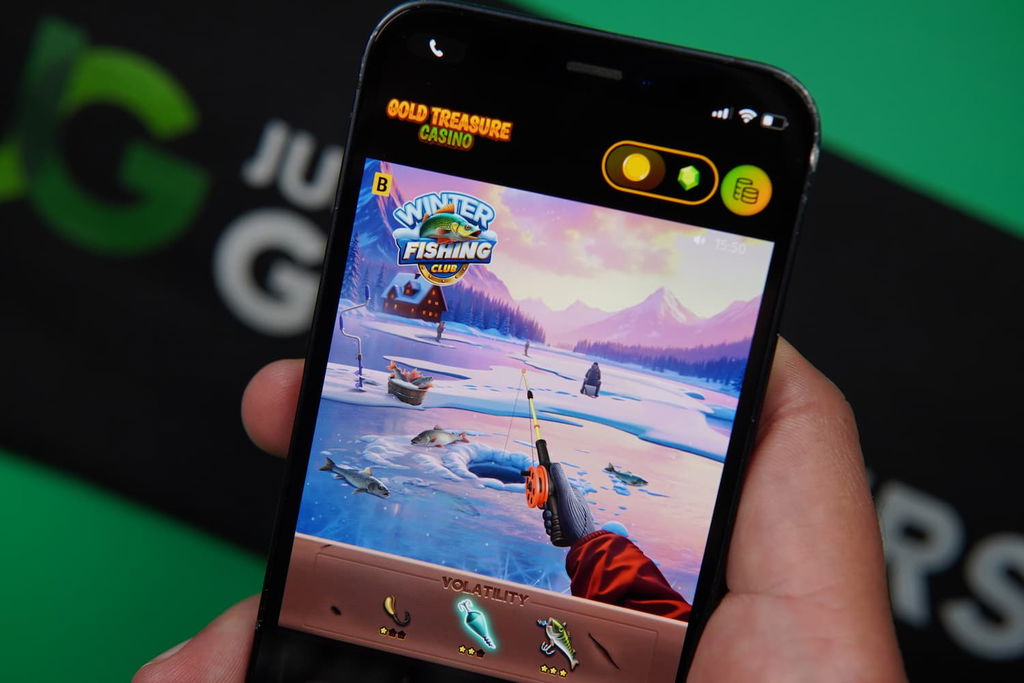 Patrik Lidin holding an iPhone with the Gold Treasure casino in-game mobile page loaded on the webpage.