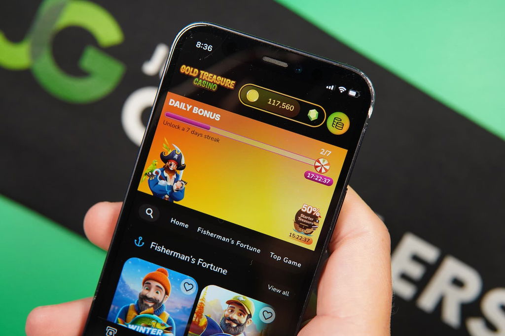 Patrik Lidin holding an iPhone with the Gold Treasure casino landing page loaded on the webpage.