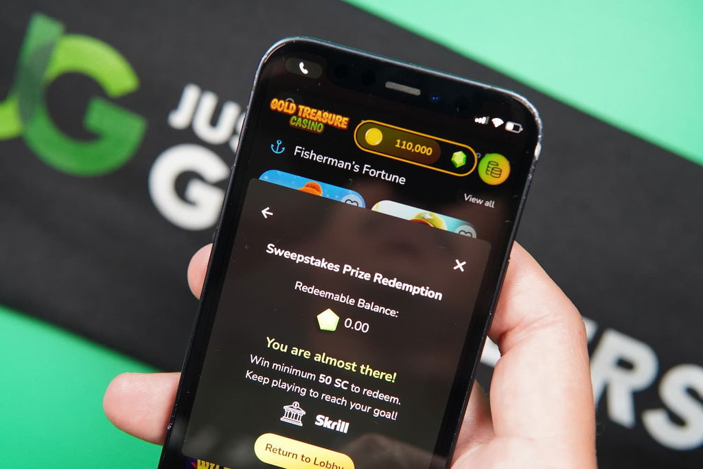 Patrik Lidin holding an iPhone with the Gold Treasure casino Redemptions page loaded on the webpage.