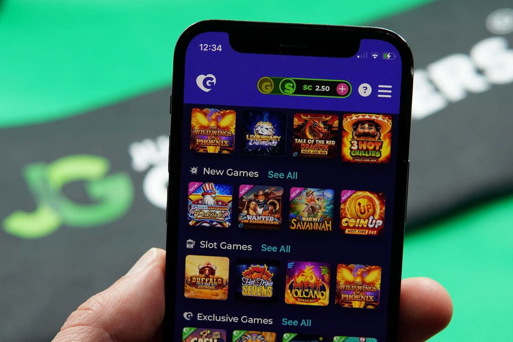 Patrik Lidin holding an iPhone with the Golden Hearts Games casino game library page loaded on the webpage.
