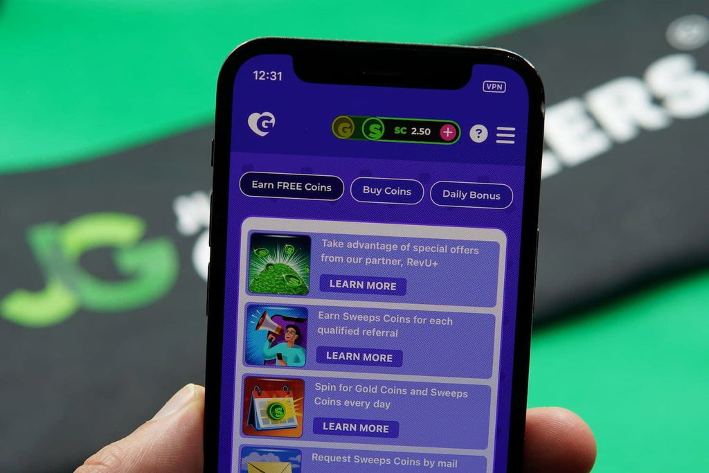 Patrik Lidin holding an iPhone with the Golden Hearts Games casino promotions page loaded on the webpage.