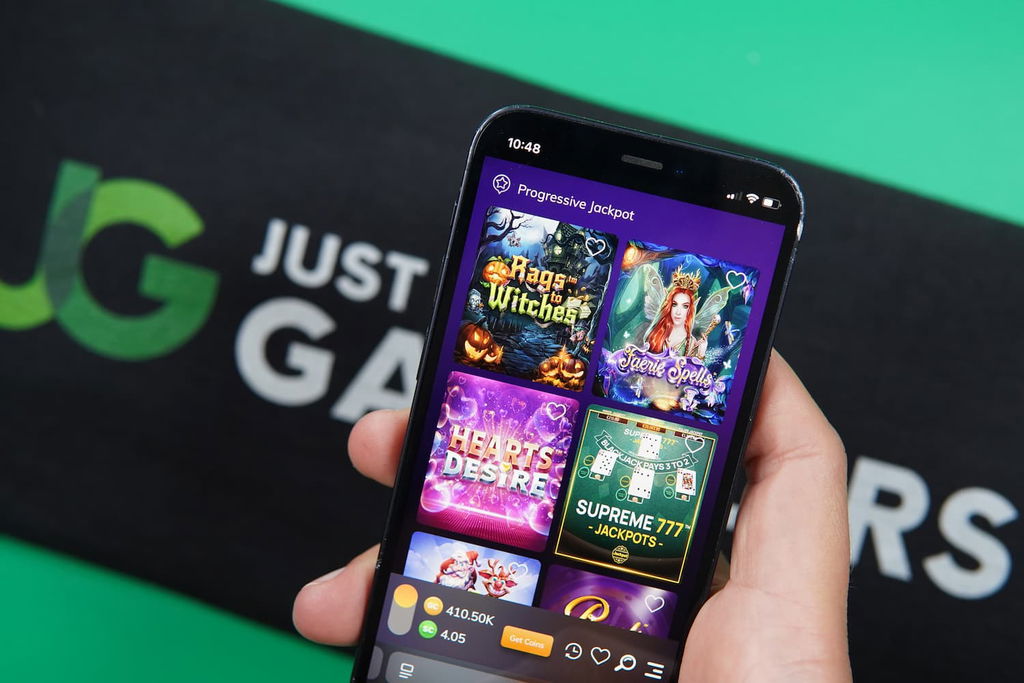 Patrik Lidin holding an iPhone with the GoldNLuck casino game library page loaded on the webpage.