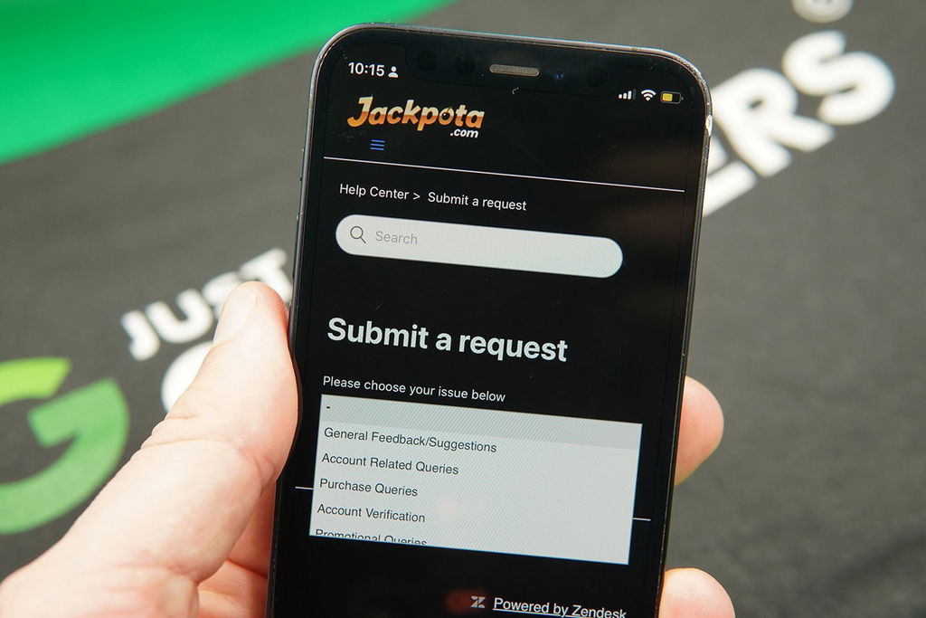 Patrik Lidin holding an iPhone while using the Jackpota customer support.
