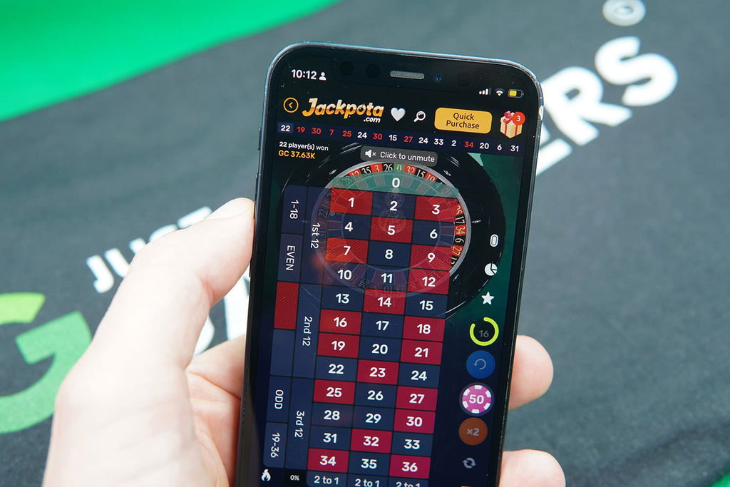 Patrik Lidin holding an iPhone with Jackpota casino game Live Roulette showing.