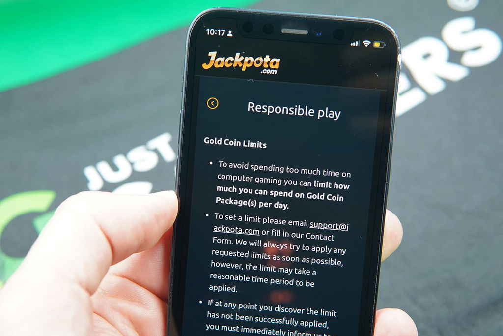 Patrik Lidin holding an iPhone with the Jackpota responsible gambling page showing.