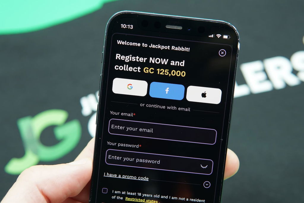 Patrik Lidin holding an iPhone with the JackpotRabbit casino Registration Page loaded on the webpage.