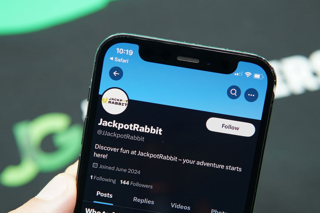 Patrik Lidin holding an iPhone with the JackpotRabbit casino X Page loaded on the webpage.