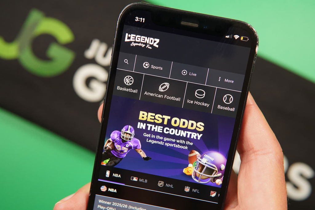 Patrik Lidin holding an iPhone with the Legendz casino sports betting page loaded on the webpage.