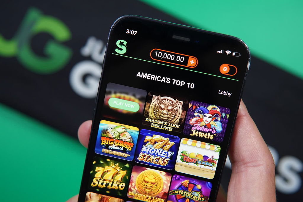 Patrik Lidin holding an iPhone with the LoneStar casino game library page loaded on the webpage.