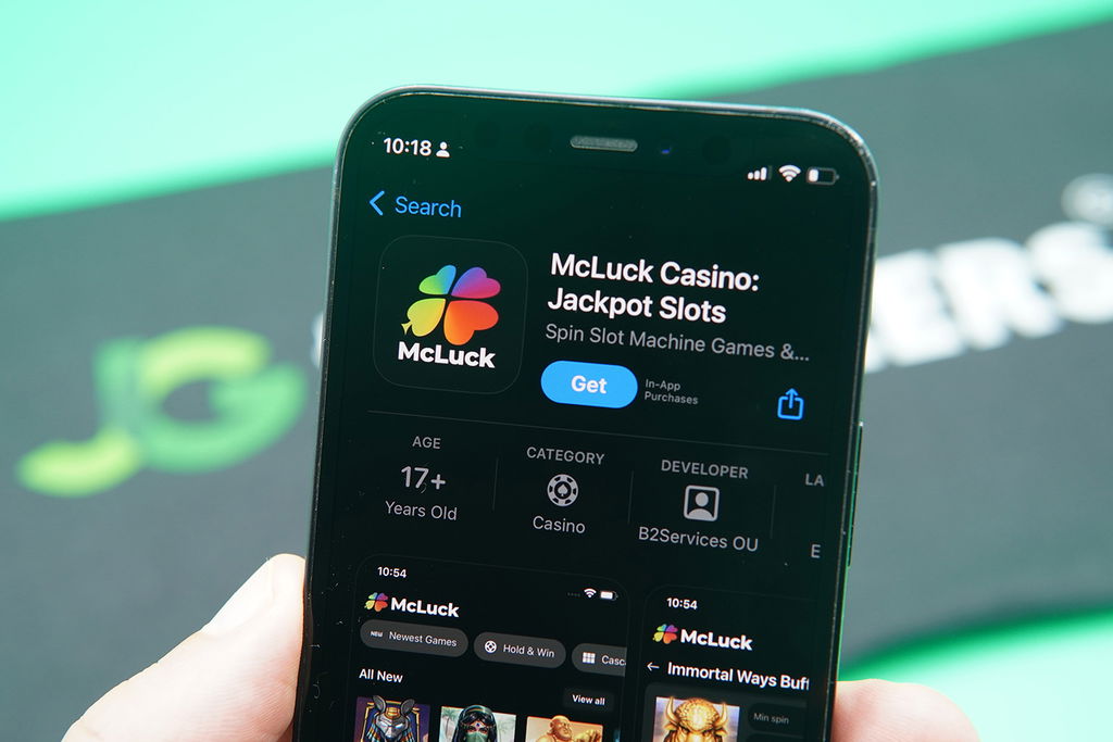 Patrik Lidin holding an iPhone with the McLuck app in Apple App Store.