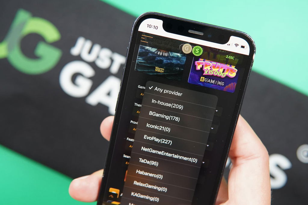 Patrik Lidin holding an iPhone with the Midas Jackpots casino providers page loaded on the webpage.