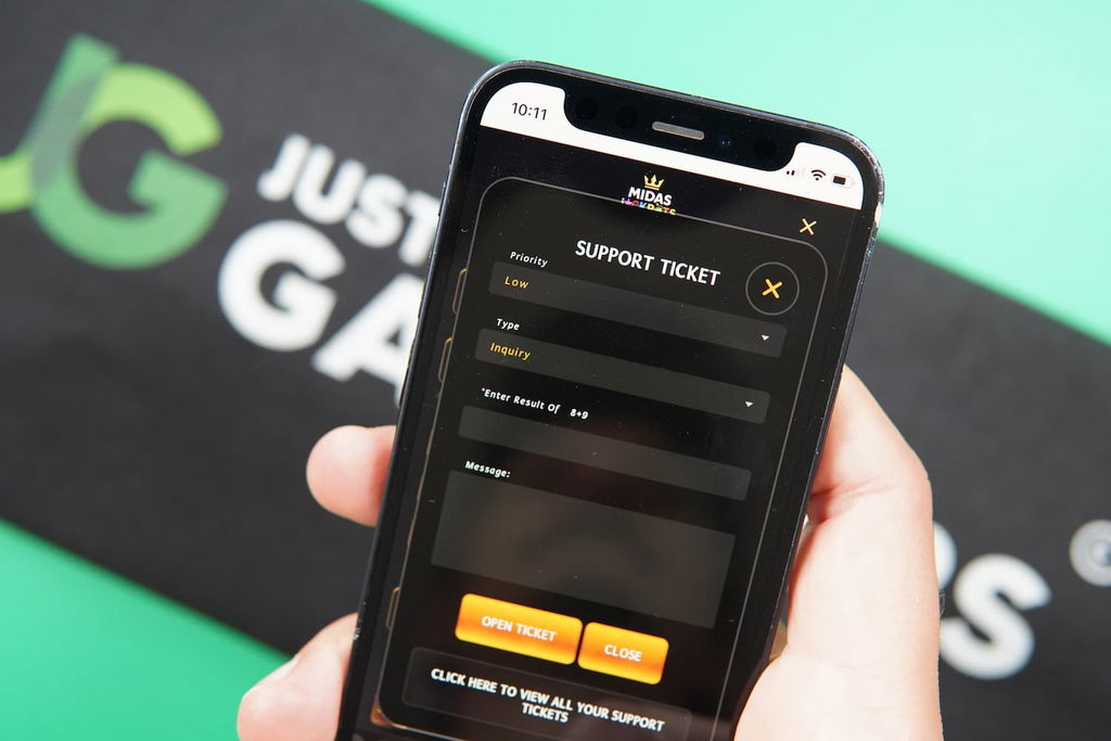 Patrik Lidin holding an iPhone with the Midas Jackpots casino support page loaded on the webpage.
