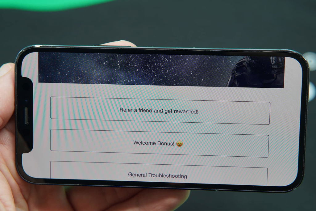 Patrik Lidin holding an iPhone with the Milky Star Slots casino support page loaded on the webpage.