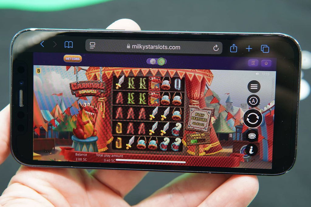 Patrik Lidin holding an iPhone with the Milky Star Slots casino mobile game loaded on the webpage.