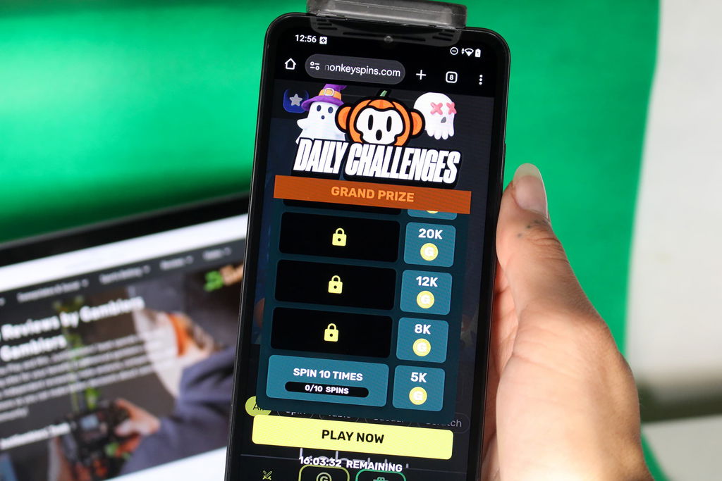 Angela Zillich holding an iPhone with the Monkey Spins casino daily rewards page loaded on the webpage.