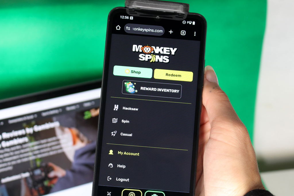 Angela Zillich holding an iPhone with the Monkey Spins casino menu page loaded on the webpage.