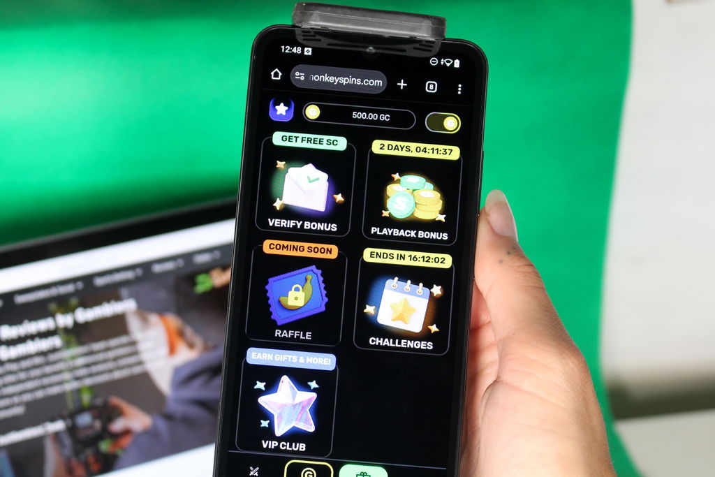 Angela Zillich holding an iPhone with the Monkey Spins casino promotions page loaded on the webpage.