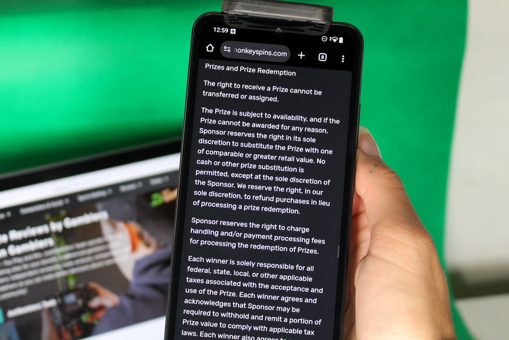 Angela Zillich holding an iPhone with the Monkey Spins casino redemptions page loaded on the webpage.