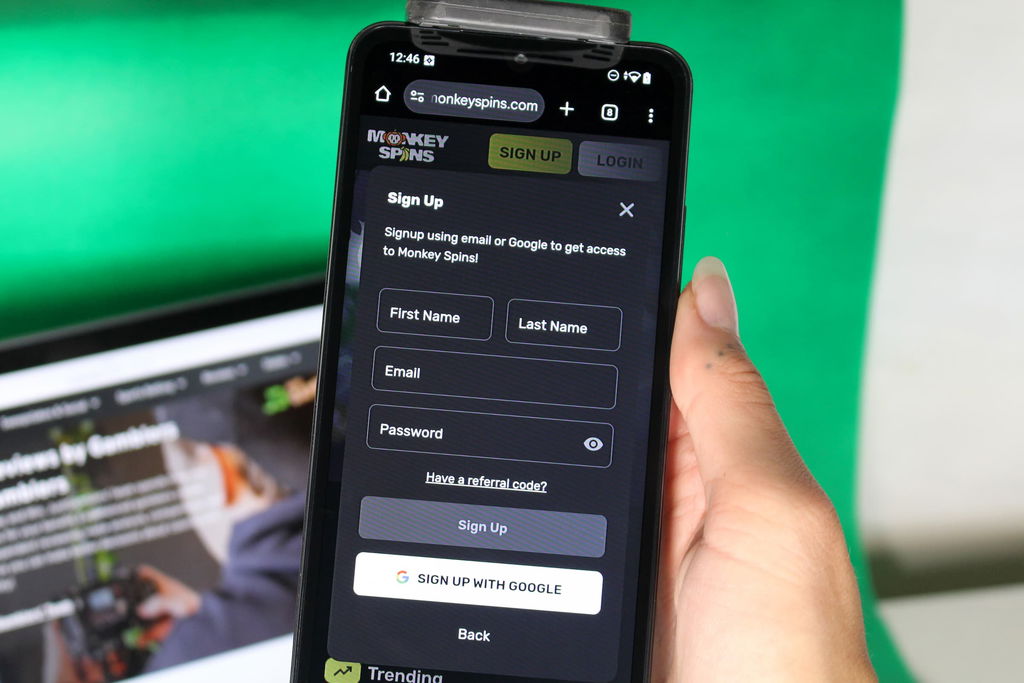 Angela Zillich holding an iPhone with the Monkey Spins casino registration page loaded on the webpage.