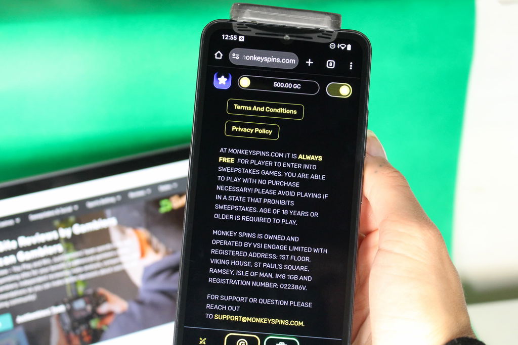Angela Zillich holding an iPhone with the Monkey Spins casino Terms and Conditions page loaded on the webpage.